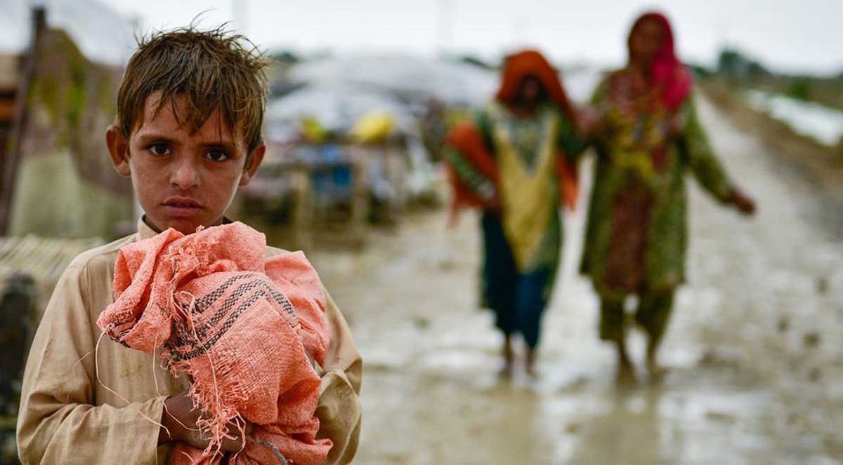 Child sitting near dried land showing effects of drought and climate change in Pakistan