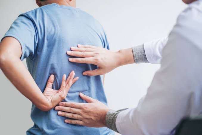 Doctor examining patient with back pain – spinal health prevention habits